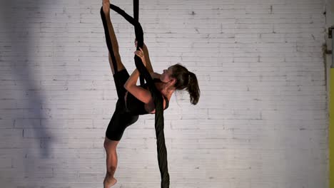 bailarina de danza aérea practicando una rutina mientras cuelga, mujer acróbata realizando acrobacias