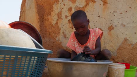 low angle of african little black cue child children washing dishes in remote rural village of africa