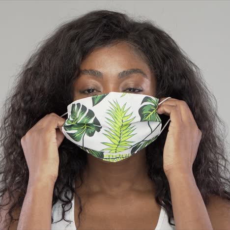 cheerful black woman putting on cloth mask