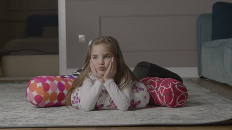 a cute little playful caucasian girl lying on the floor looking at the camera and blowing a kiss