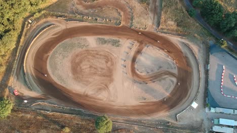 Motocross-running-on-a-circular-dirt-track,-top-down-aerial-drone-footage