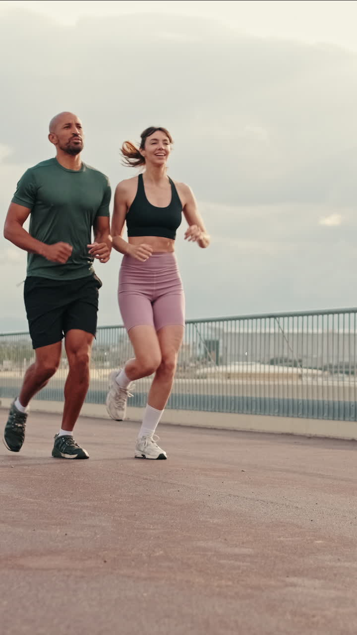 Coppia atletica che corre insieme su un ponte urbano