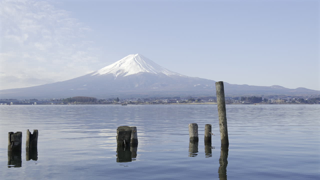 Magnificent view of Mount Fuji reflecting in the calm waters of Lake Kawaguchi. The snow-capped peak and tranquil surroundings create a peaceful atmosphere in early morning light