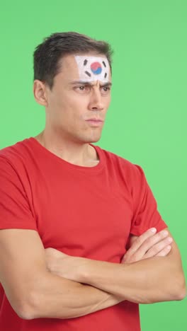 man with south korean flag painted looking away with serious expression