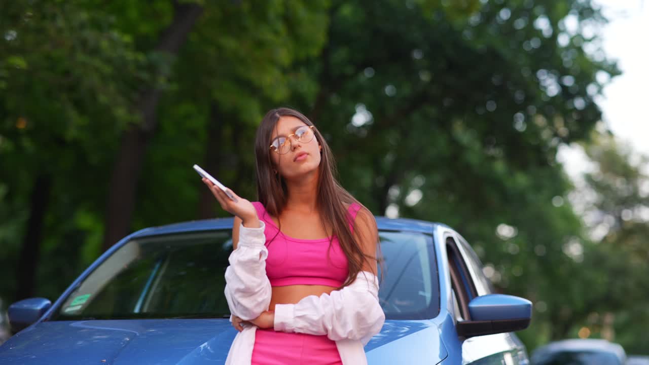 joven hablando por teléfono cerca de un coche azul