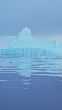 big iceberg ice formation in ocean sea water, large amazing shapes bizarre icebergs in antarctica scenery vertical video for social media, instagram reels and tiktok, antarctic peninsula landscape