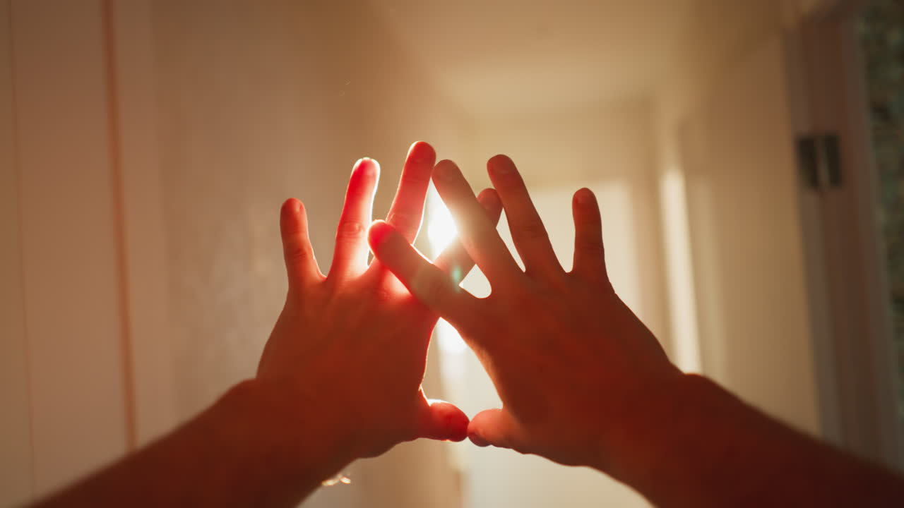 vista en primera persona caminando, manos bloqueando la luz del sol cegadora, silueta cálida contra un fondo brillante, toma de cámara de mano