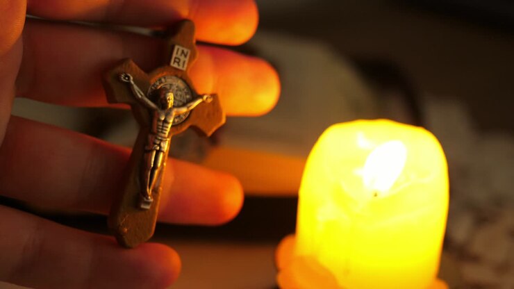 Croce con Cristo Gesù al crepuscolo illuminata dalla luce di una candela