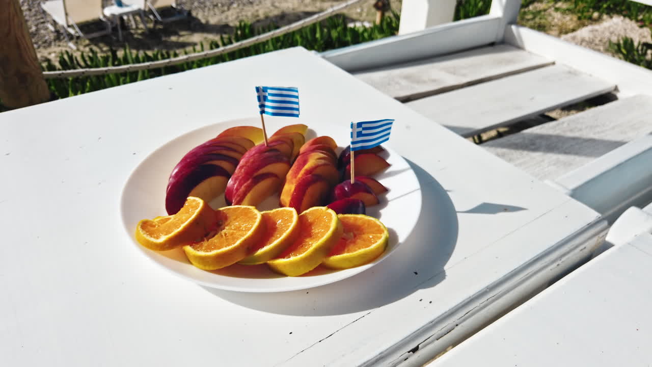 Skivede frukter på et fat med greske flagg, Egeerhavet i bakgrunnen, Hellas