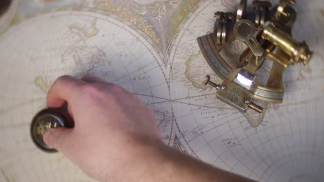 a man uses an antique compass to plot a course on a vintage world map with a sextant in the background