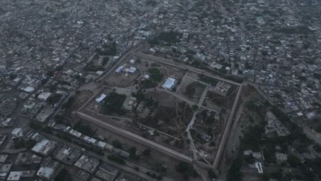 Drone-Aéreo-Inclinado-Hacia-Abajo-Disparado-Sobre-Una-Antigua-Fortaleza-Histórica-En-Una-Antigua-Ciudad-De-Umerkot,-Tharparkar,-Pakistán-Durante-La-Noche