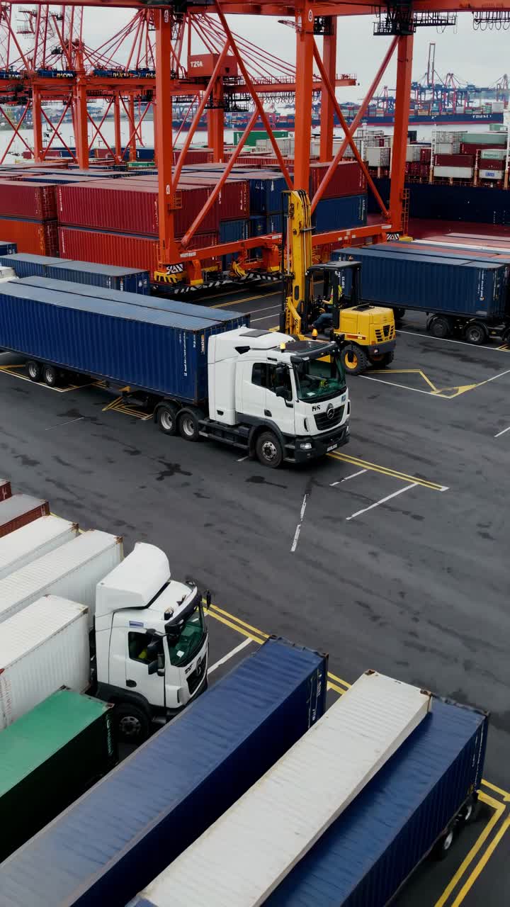 High-angle video shot of a bustling shipping port with trucks and containers, capturing the dynamic
