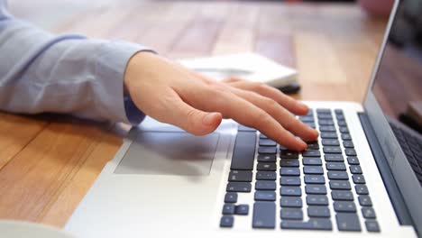 mujer trabajando en una computadora portátil mientras tiene una taza de café en el escritorio