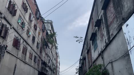 extremely polluted river channel passing through old buildings. open sewer, housing, basic sanitation. tilt down view