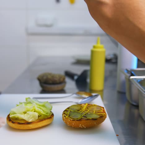 hands in latex gloves put pickles on top of fried bun. making burger on white table. fast food concept video