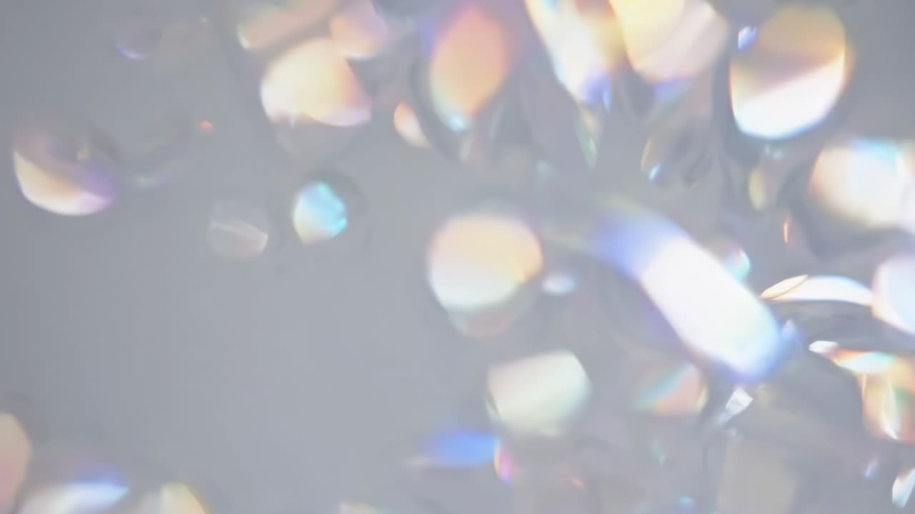 Abstract video still with a soft focus and close-up angle, featuring iridescent light reflections
