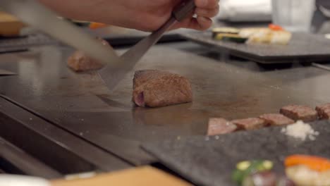Japan-Chef-cut-slice-Kobe-Wagyu-meat-over-teppanyaki-table-in-front-of-guest-shot-Marble-certified-authentic-Japanese