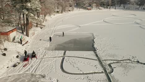 aerial, workers clearing snow on a frozen lake to create ice rink