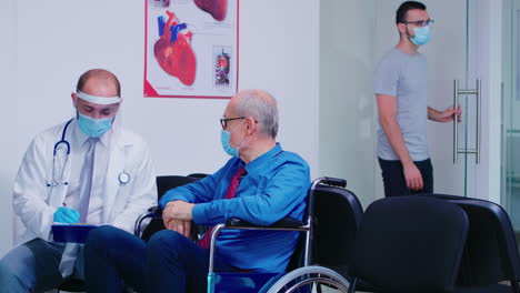 doctor consulting disabled senior man in hospital waiting area