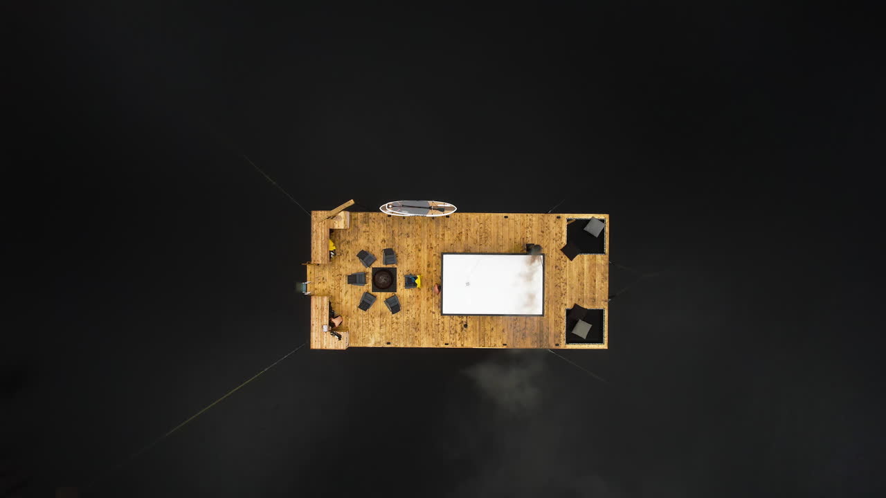 Drone top-down view of smoke escaping wood-fired cedar floating sauna, Tofino