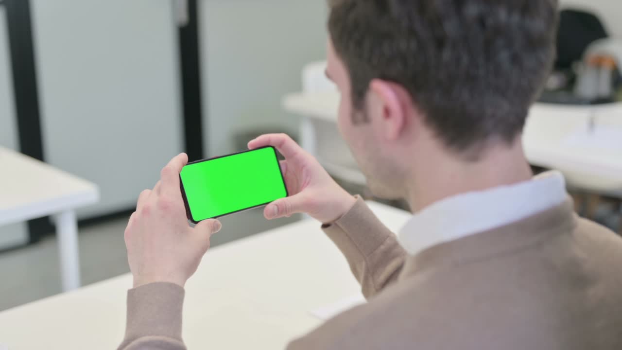 크로마 스크린 을 가진 스마트폰 을 바라보는 남자 의 뒷면