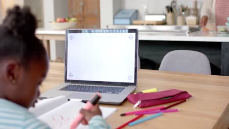 African-american-girl-learning-online-at-table-using-laptop-with-copy-space-on-screen,-slow-motion