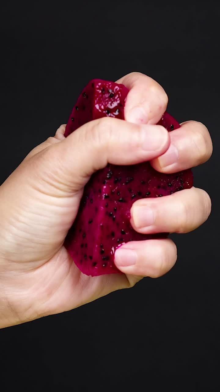 la mano exprimiendo la fruta del dragón, el jugo goteando