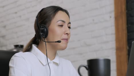 smiling woman call centre operator, customer support agent wears headset consults client online, typing on laptop, talk in internet computer chat, helpline operator secretary make conference video call