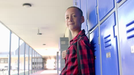 biracial boy stands by school lockers, with copy space