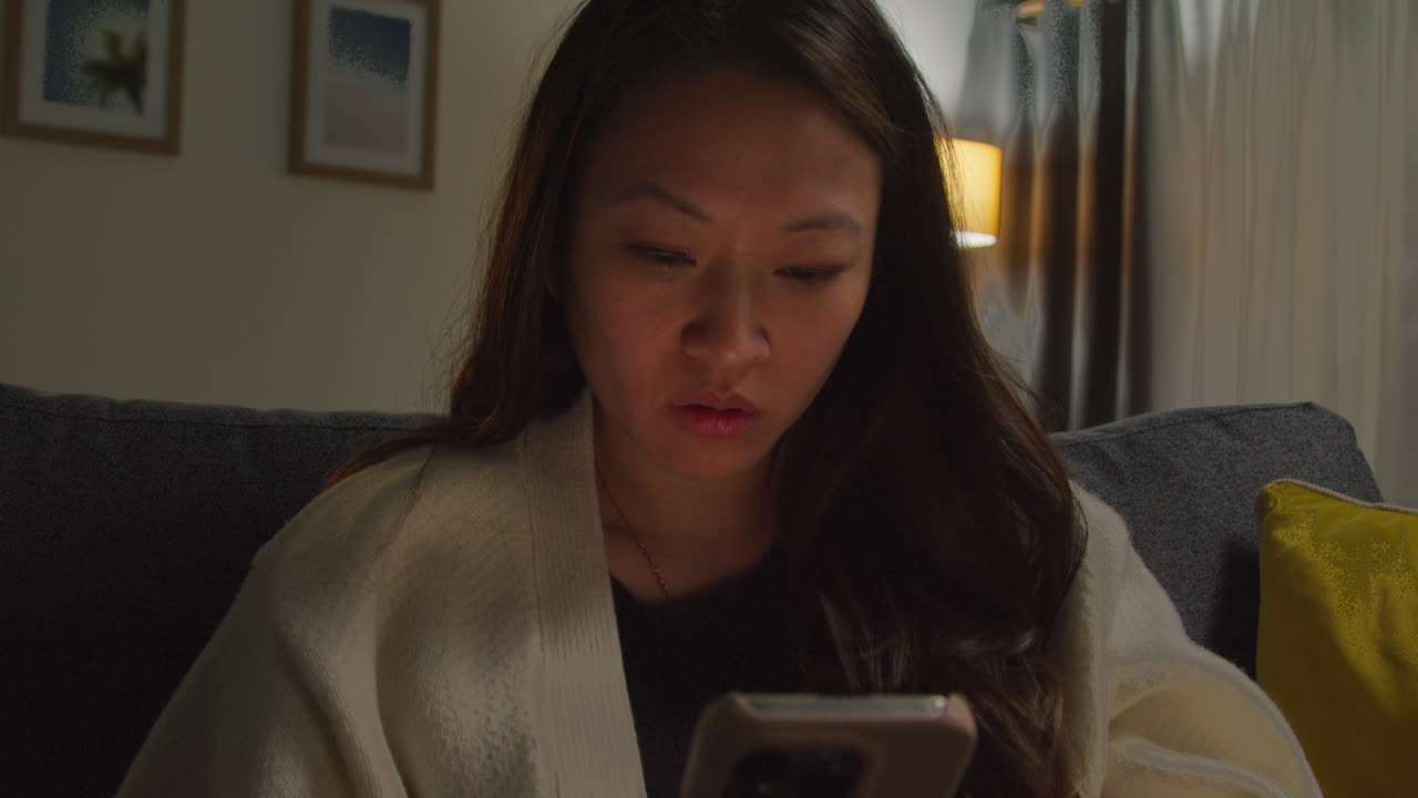 스트레스를 받고 불안한 여성은 집에서 저녁을 보내고 소파에 앉아 인터넷이나 소셜 미디어 뉴스 메시지 또는 휴대 전화에 반응합니다.