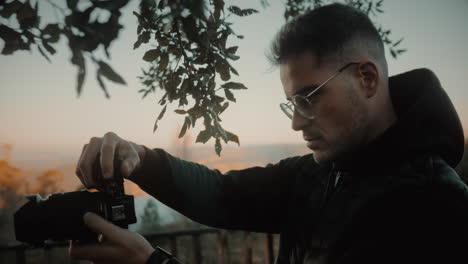 Inspired-freelance-photographer-wearing-glasses-uses-a-DSLR-mirrorless-camera-with-a-lens-to-take-detailed-photos-of-tree-trunk-texture