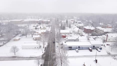 Coche-Pasando-Por-Una-Pequeña-Ciudad-Americana-En-Temporada-De-Invierno,-Vista-Aérea-De-Drones