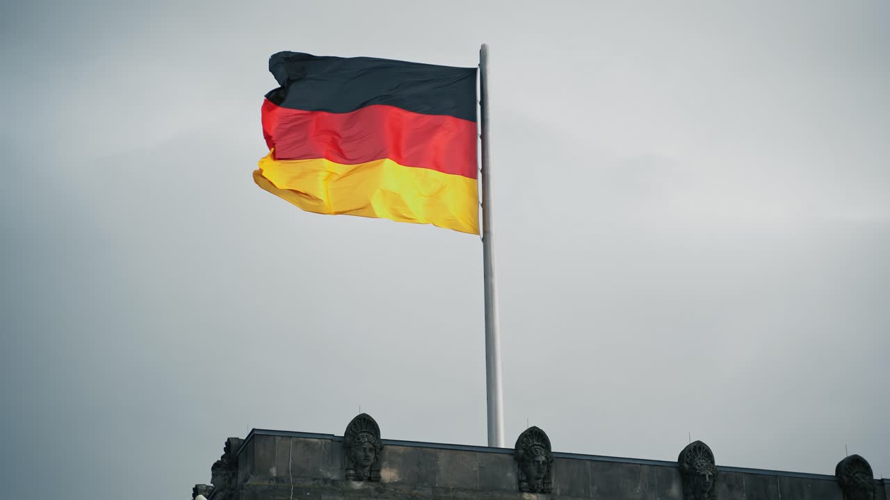 German Flag waving in stormy weather on Reichstags Building in Berlin Germany, National Symbol in ominous moody sky