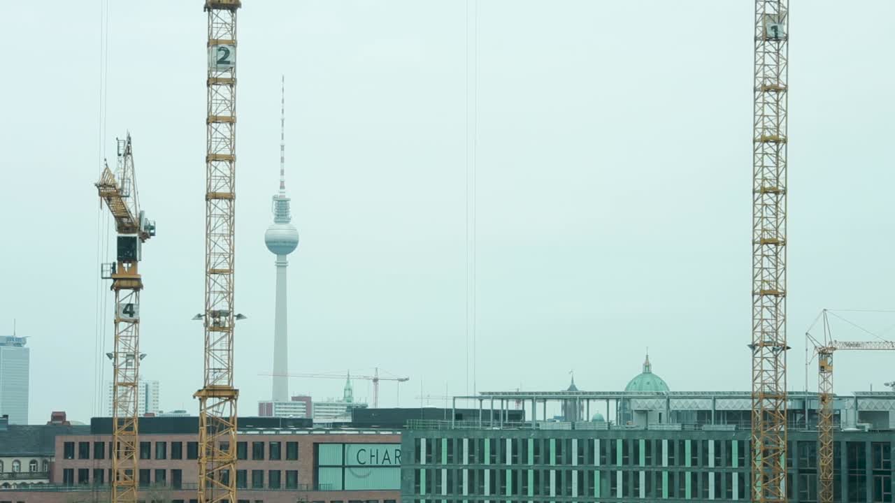 grúas de construcción que se elevan sobre berlín con el icónico fernsehturm en el fondo