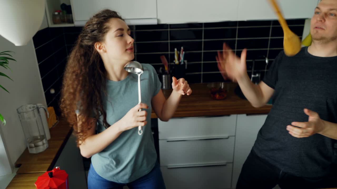 joven pareja alegre se divierten bailando y cantando mientras cocinan en la cocina en casa en las vacaciones