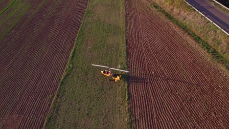 Gyroplane-turning-on-grass-rural-runway-on-sunny-afternoon,-aerial