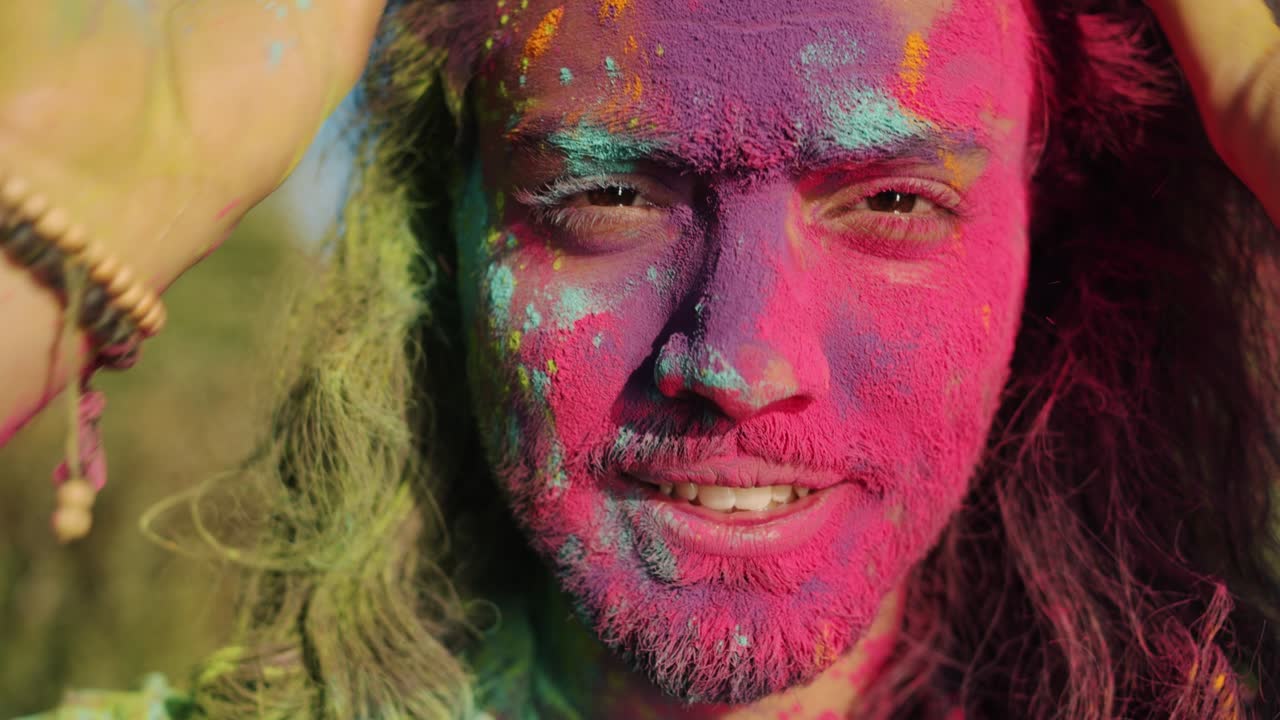 Ritratto ravvicinato di un uomo mediorientale gioioso con il viso colorato che sorride godendosi il festival Holi