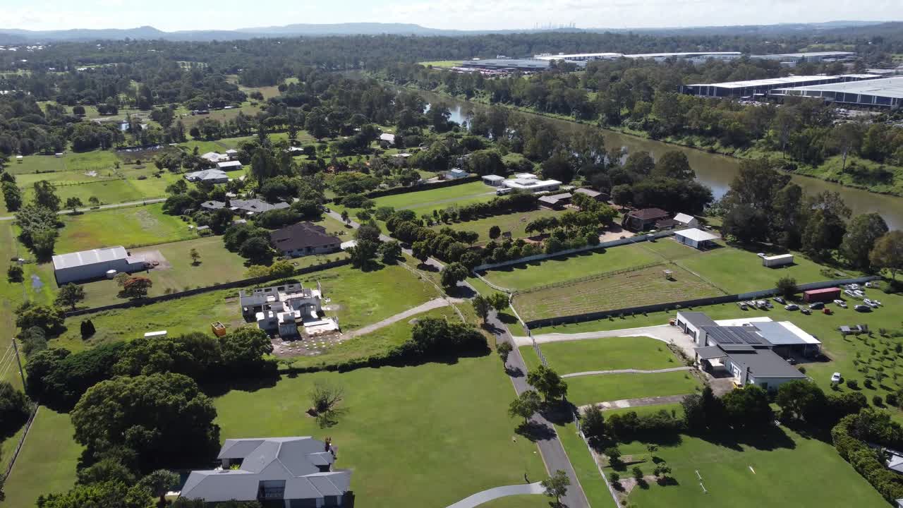 4K Aerial Video of a lush green rural suburb near a small brown river in Australia