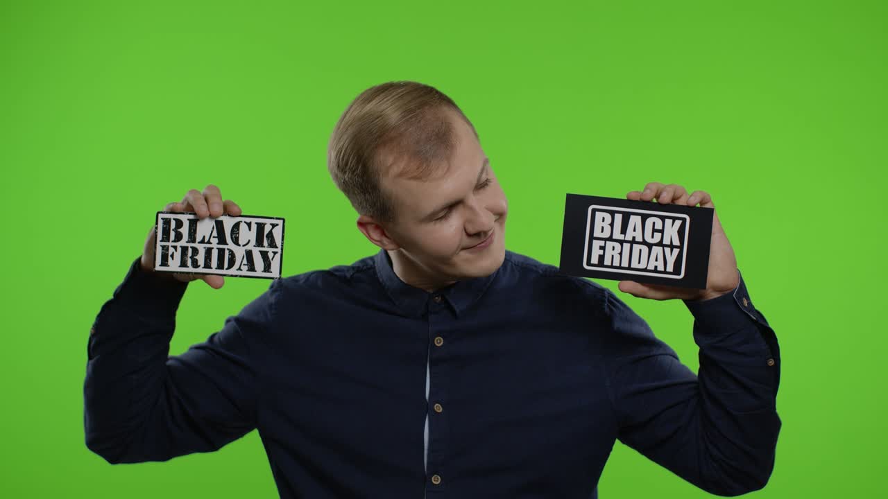 두 개의 블랙 프라이데이 문구 노트를 보여주는 기쁜 남자, 낮은 가격에 만족하는 미소