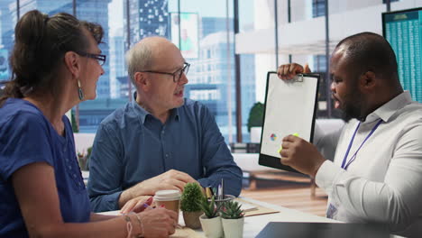 insurance broker explaining financial plans to senior couple in a modern office