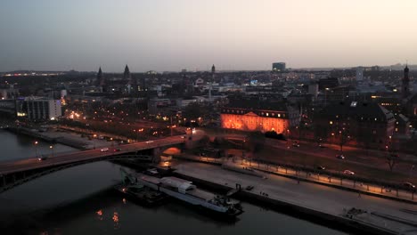 Uplifting-Drone-shot-by-night-over-Mainz-right-after-magic-hour-on-a-warm-spring-day-showing-the-city-of-Biontech-in-the-back