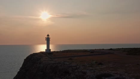 sun reflected on still sea, white lighthouse on rocky cliff, dolly out