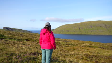 mujer se detiene a caminar para admirar el paisaje cerca del lago sorvagsvatn, islas feroe