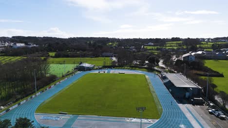 sports stadium flight over stadium, not in use showing field, track and grandstand on bright sunny day