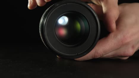 male hands opening and closing the aperture of the removed lens.