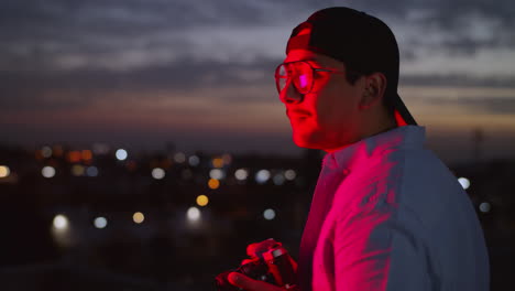 young man taking pictures of the city at night next to a red neon light