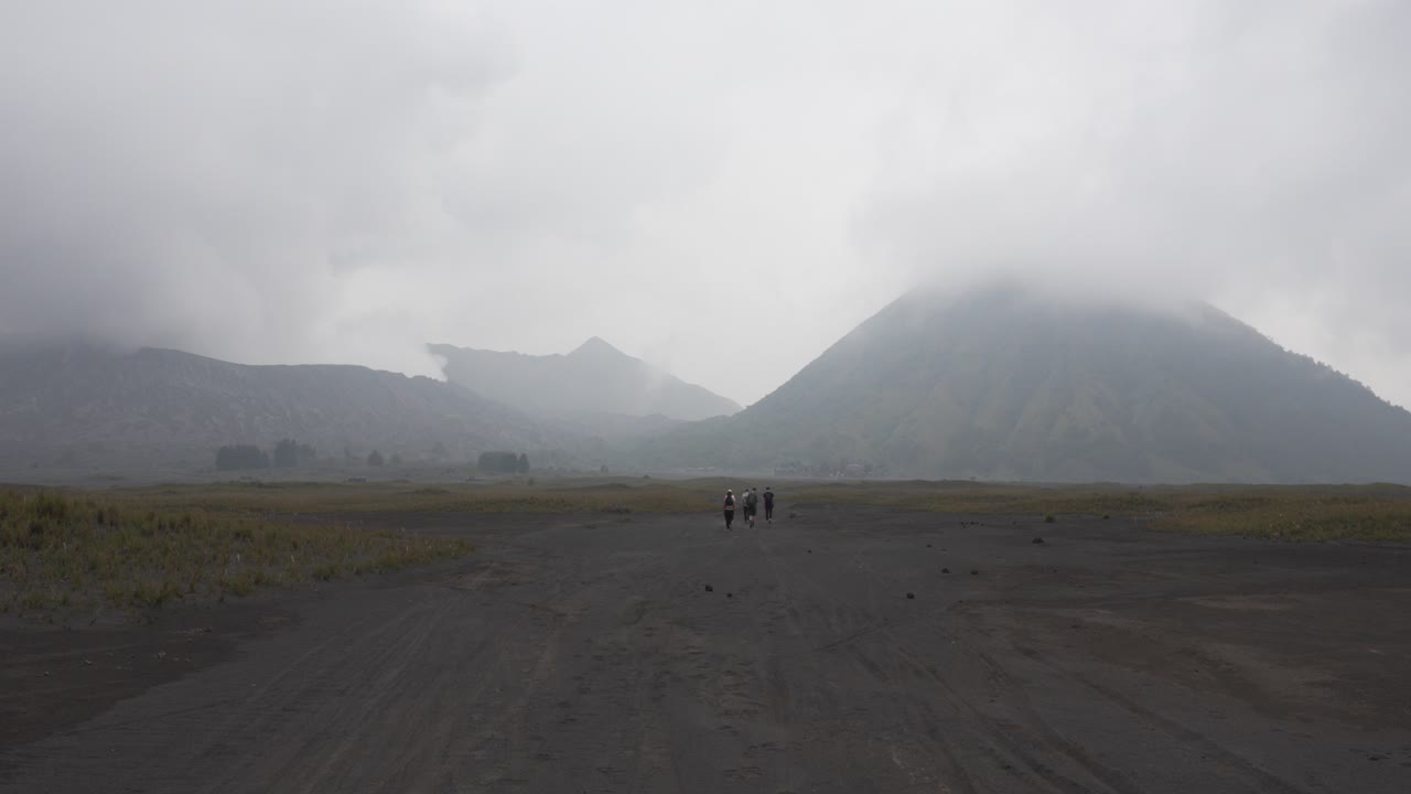 People group trek hike toward Mount Bromo active volcano crater volcanic landscape Java Indonesia