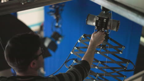 technician adjusting overhead lighting equipment, positioning light fixture carefully in a studio environment, preparing lighting rig for precise production use, focusing on alignment and setup