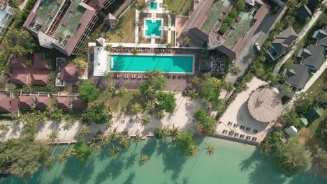 aerial view over a coastal beach hotel with deep blue swimming pool