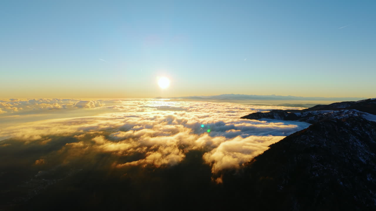 Ripresa aerea del sole che sorge sulle Alpi, paesaggio invernale tranquillo di montagna, nuvole mattutine soffici